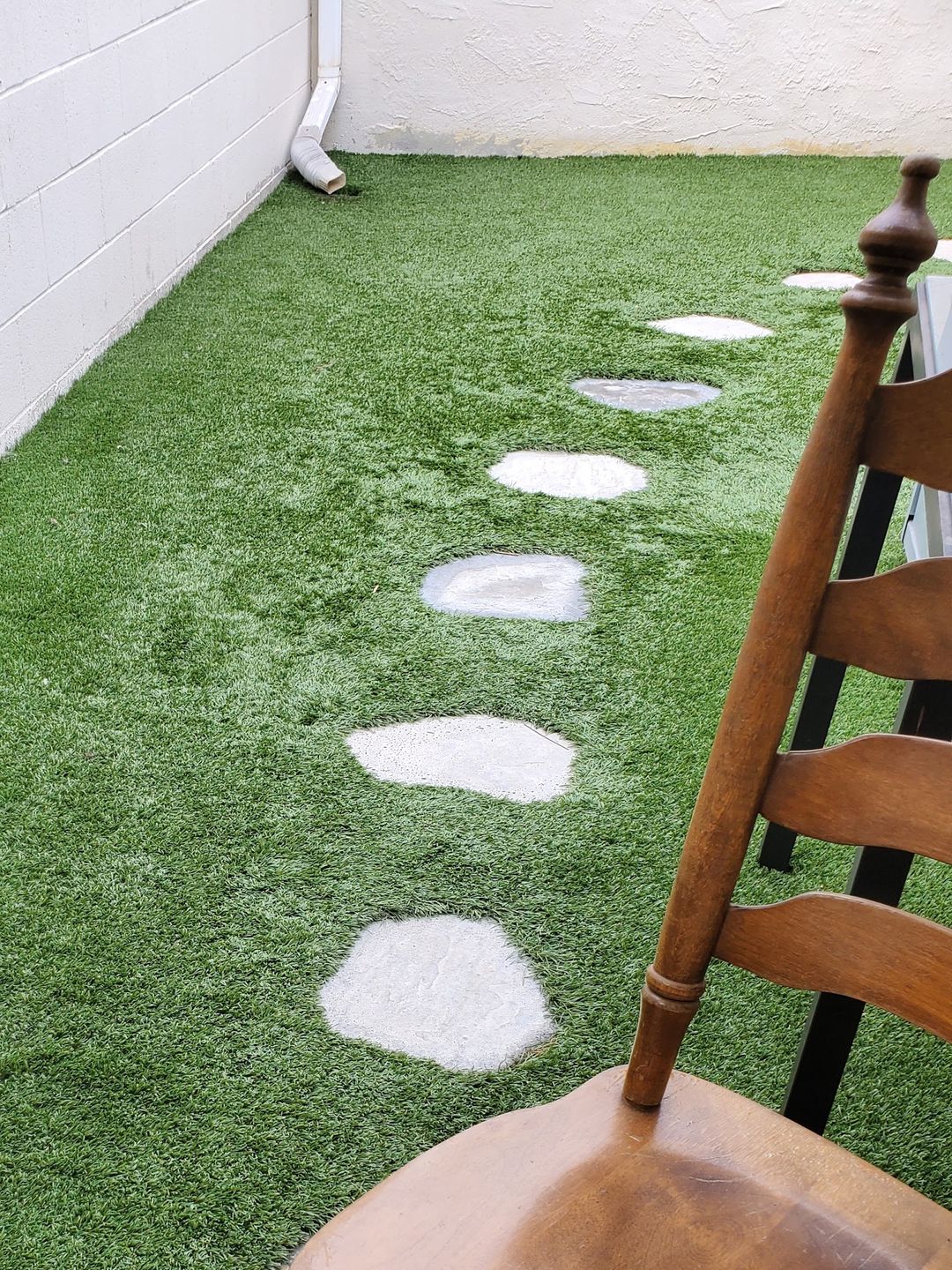 Artificial turf laid along a narrow side yard with stepping stones set into it
